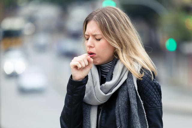 Mujer joven tosiendo en la calle