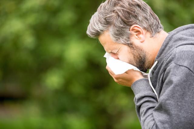 Hombre con alergia tosiendo en la naturaleza