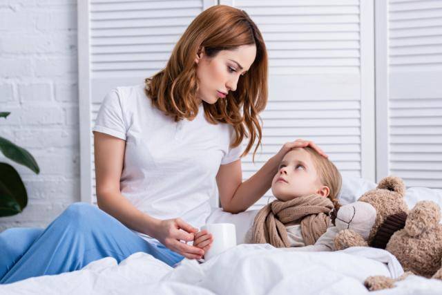 Madre cuidando hijo enfermo en cama