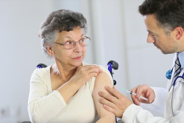 Médico poniendo una inyección en brazo a mujer mayor